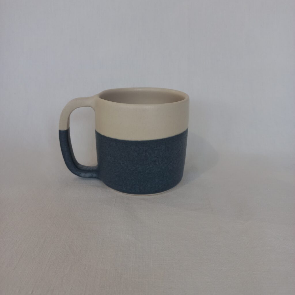 cette image montre une tasse bicolore bleue et blanche en grès avec anse 