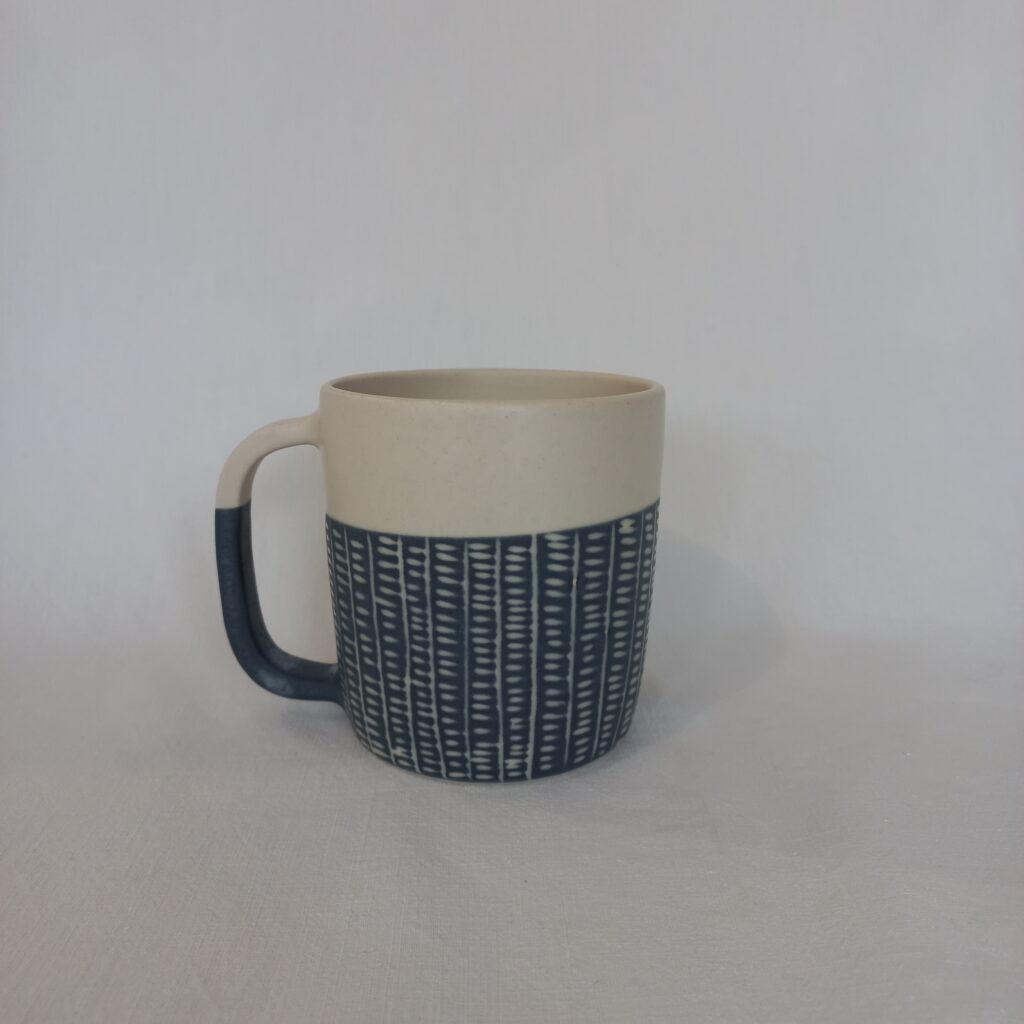 cette image montre une tasse bicolore bleue et blanche en grès avec anse sgraphitée motifs rails