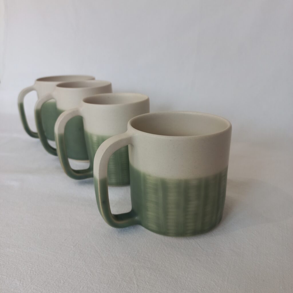 cette image montre un lot de 4 tasses en grès bicolores blanc et vert, le vert est sgraphité en motif rail